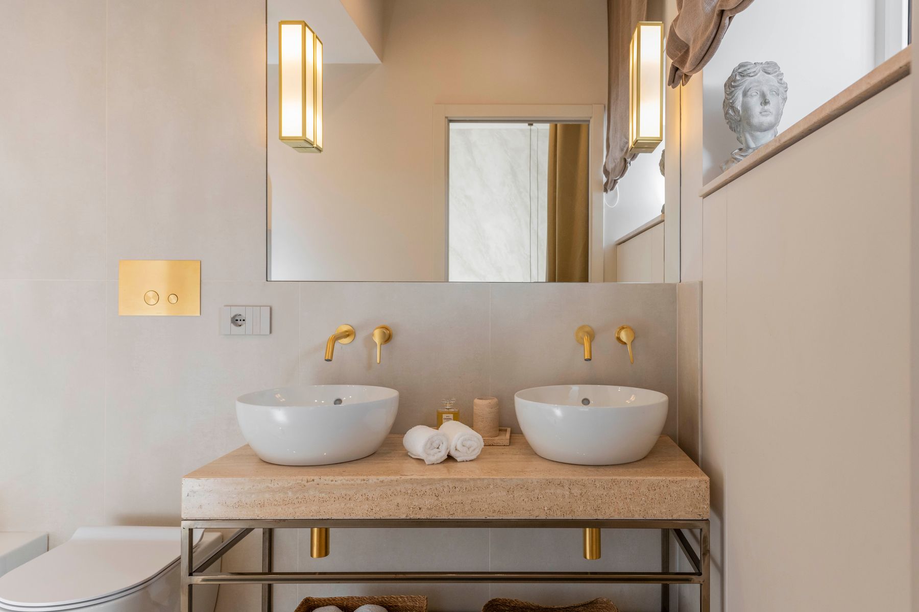 Bathroom with double vanity, brass sconces and classical bust – Domus Aurelia